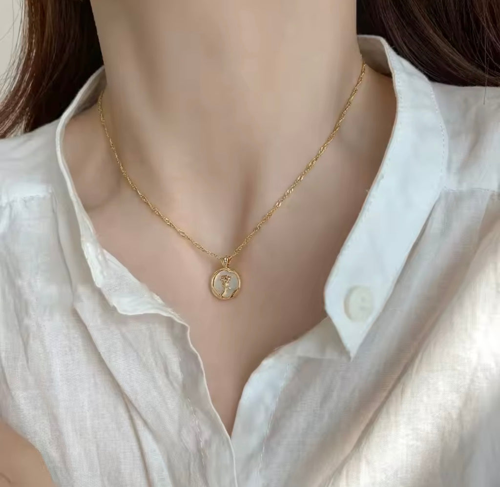 model wearing the Rosa del Mar  necklace with a coin pendant against a white shirt background
