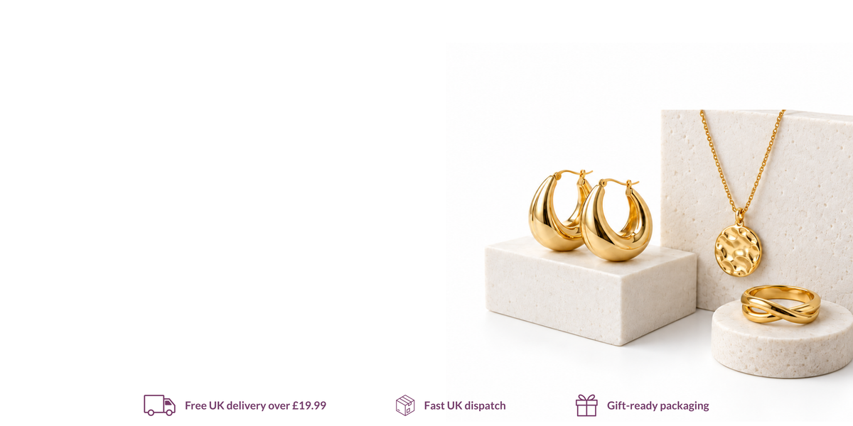 Waterproof gold necklace, hoop earrings and ring displayed on white stone stands.