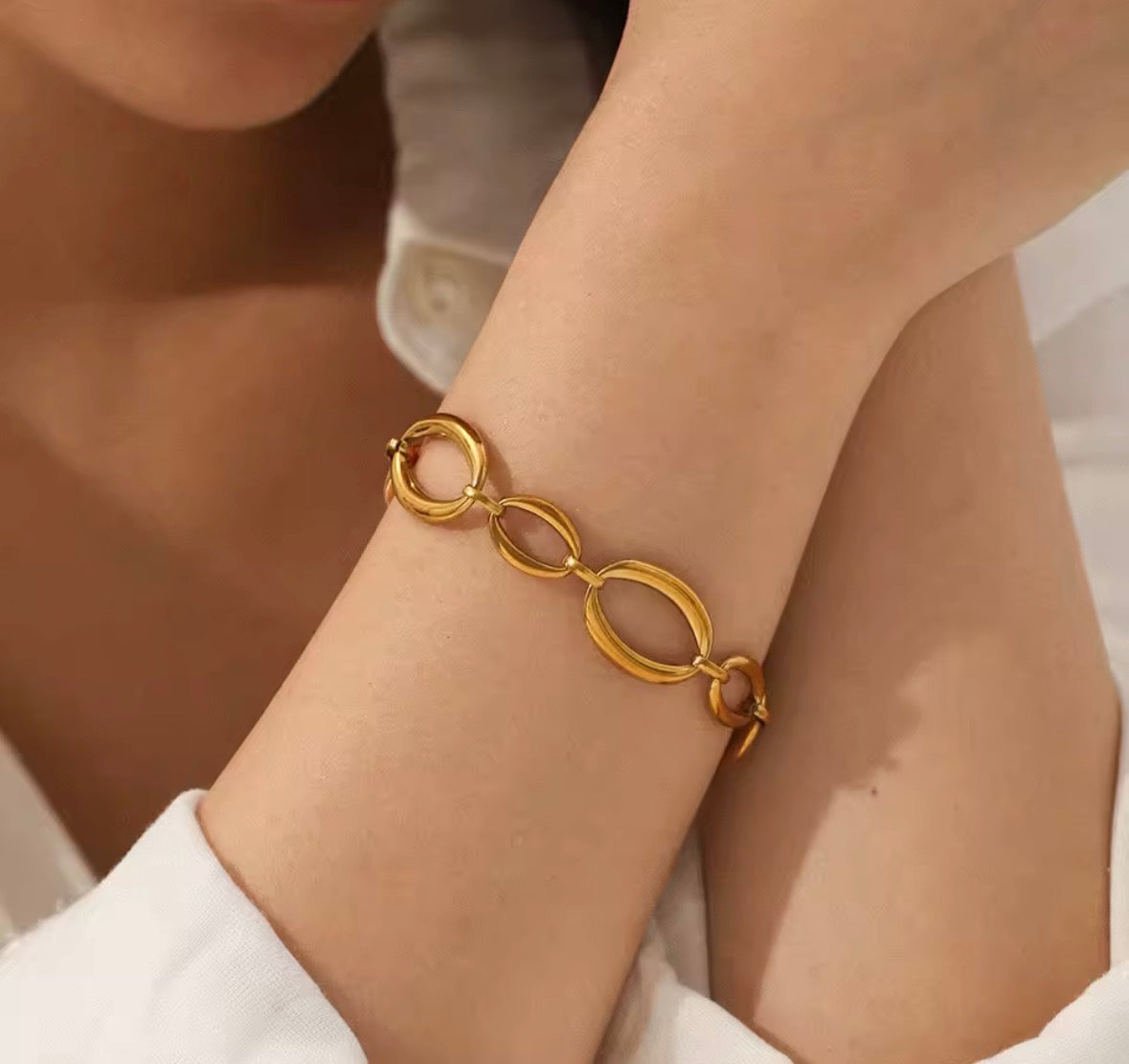 Close-up of The Sorevia gold oval link bracelet styled on a woman's wrist